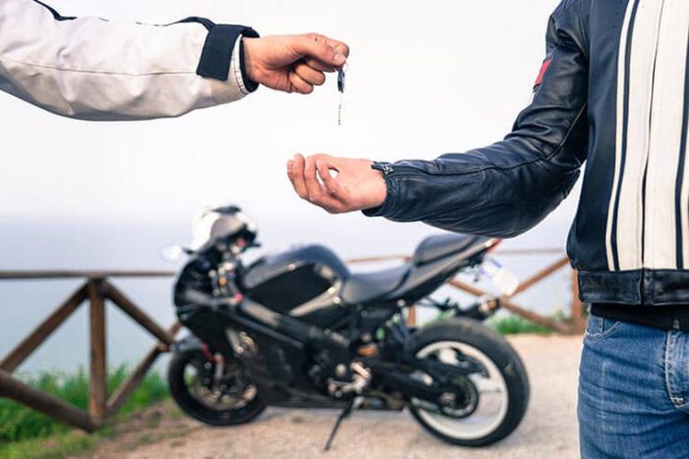 تصویری از دو فرد که درحال تبادل سویچ موتور سیکلت هستند به همراه موتور سیکلتی در گوشه تصویر که تداعی کننده راهنمای خرید موتور سیکلت دست دوم است.