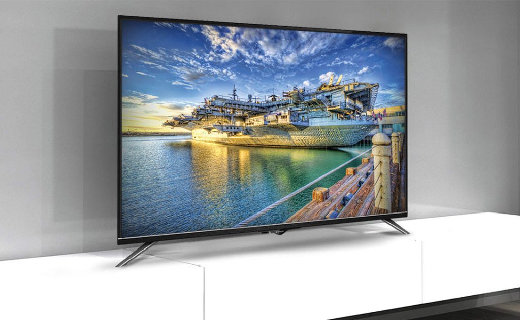 تصویری از یک تلویزیون رنگی اسنوا که در کنار یک دیوار طوسی رنگ قرار گرفته است.